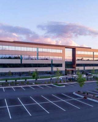 Evening shot of office building exterior with large parking lot Evening shot of office building exterior with large parking lot
